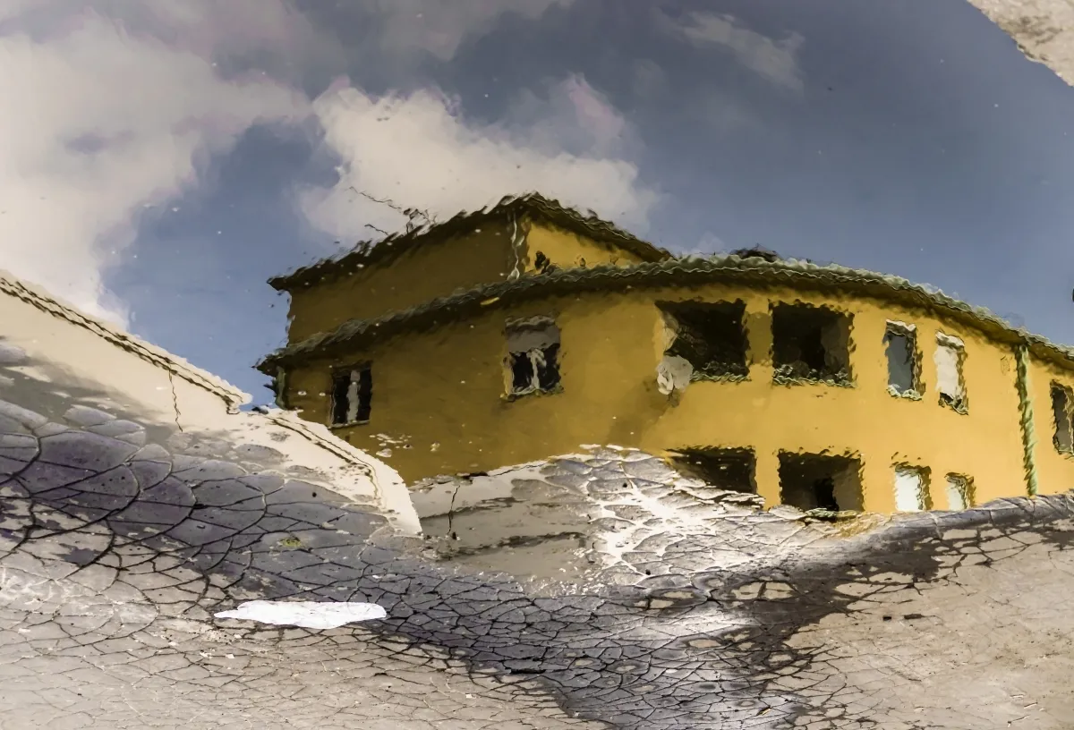 Yellow building reflected in dirty snow and meltwater
